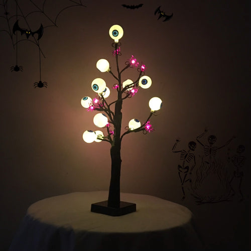 Schaurige Augenbaum-Lampe leuchtet im dunklen Raum mit warmen Augen und lila Spinnen