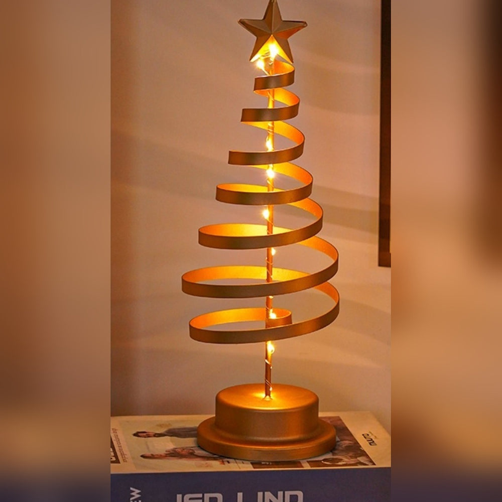 Goldene Spiralbaum-Lampe mit warmem LED-Licht als stimmungsvolle Winterdeko auf Büchern