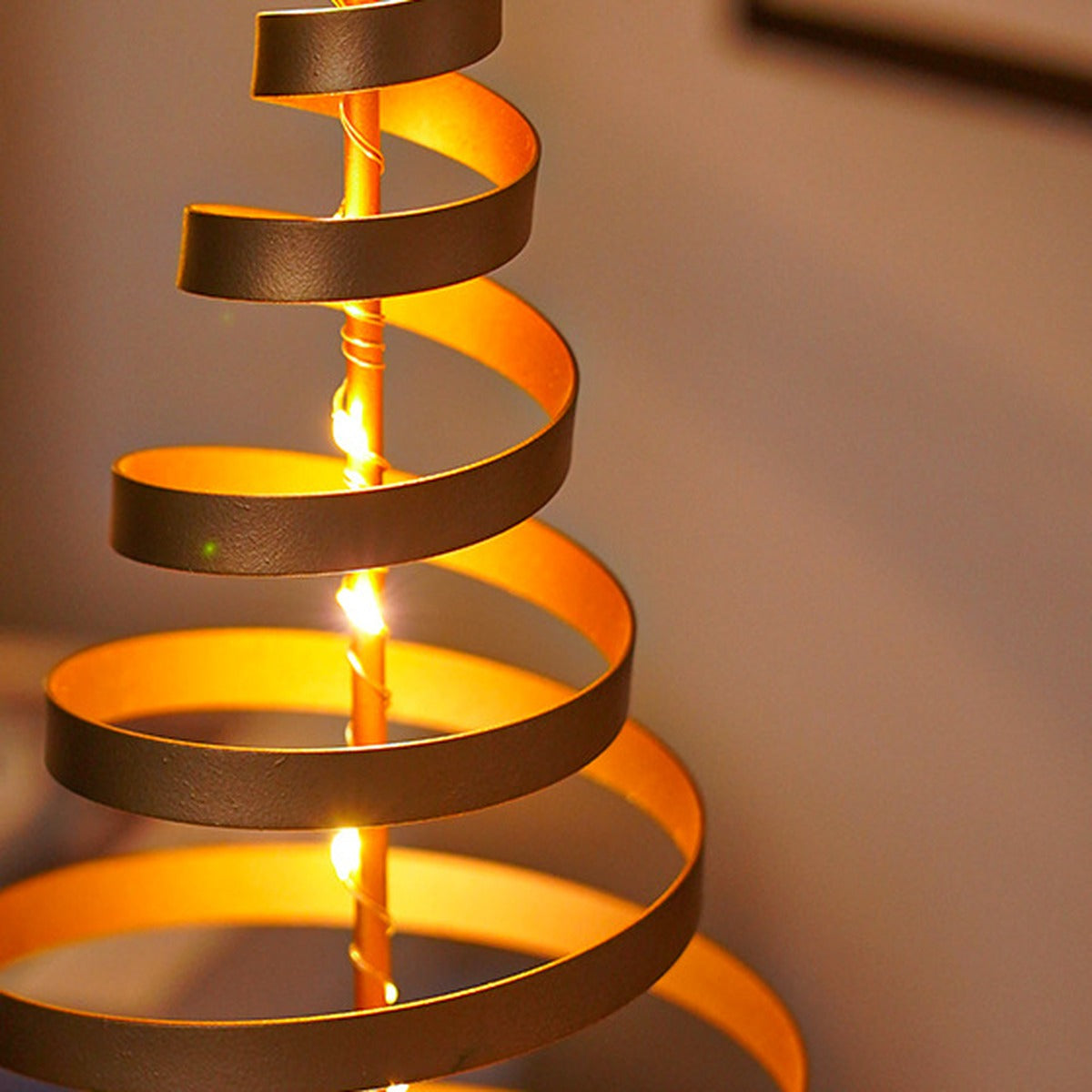 Nahaufnahme der goldenen Metallspirale der Spiralbaum-Lampe mit leuchtenden warmweißen LEDs